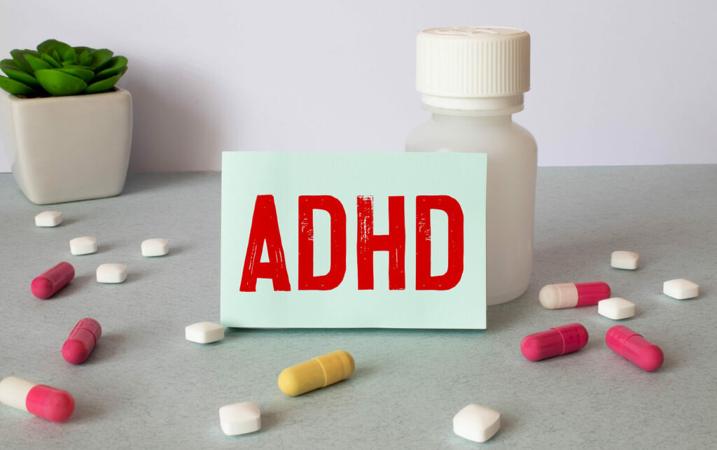 ADHD on notebook sheet against a medication bottle with pills laying around it. Struggling with your ADHD symptoms and unsure how to manage them? With medication management you can begin to reduce your symptoms soon. 