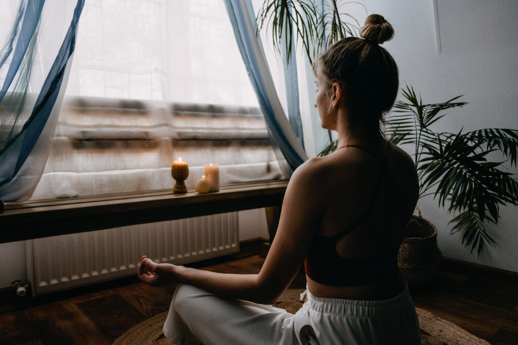Young woman sitting on floor doing yoga exercise and meditation at home. ADHD can be challenging even on your best day. Learn tips from a New York therapist on how to better manage ADHD without medication. Learn here. 