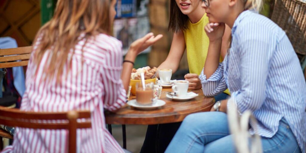 Group of women socializing happily at a cafe representing someone who overcame social anxiety and ADHD with ADHD-Focused Therapy for Anxiety in NY, NY.
