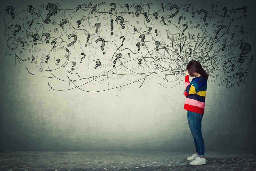 A woman stands covering her face surrounded by question marks and exclaimation points. This could symbolize overwhelm an ADHD therapist in New York, NY can help you overcome. Learn more about mindfulness and ADHD in New York, Ny by searching for online ADHD therapy in NY.
